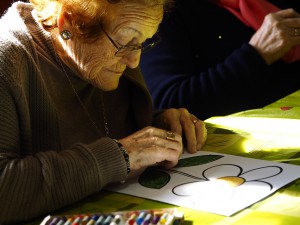 Fotografía en la que se puede ver una anciana pintando una flor